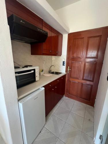 a small kitchen with wooden cabinets and a microwave at Electra Studios in Palaiochóra