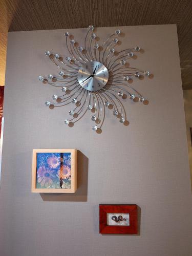 a clock hanging on a wall with a picture at Noctis豊田 ジャグジー肩湯付お風呂75型TV 最大12名宿泊可能 in Toyota