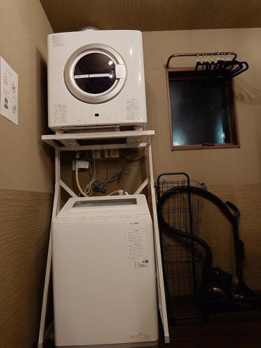 a microwave on top of a refrigerator in a kitchen at Noctis豊田 ジャグジー肩湯付お風呂75型TV 最大12名宿泊可能 in Toyota