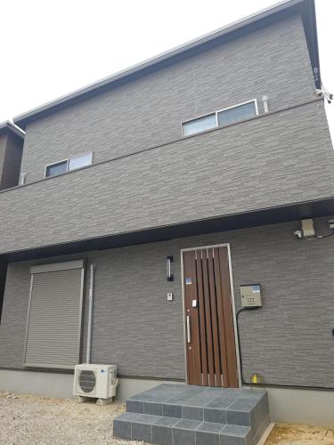 a house with a brown door on the side of it at Noctis豊田 ジャグジー肩湯付お風呂75型TV 最大12名宿泊可能 in Toyota