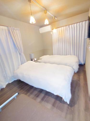 a bedroom with two beds with white sheets at Noctis豊田 ジャグジー肩湯付お風呂75型TV 最大12名宿泊可能 in Toyota