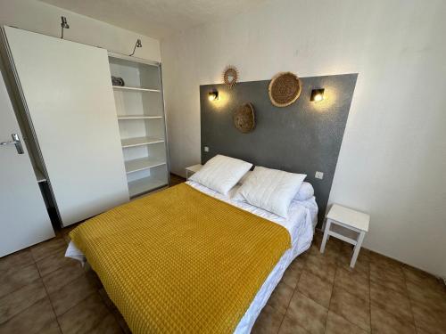 - une petite chambre avec un lit et une couverture jaune dans l'établissement Bas de Villa Terrasse & Clim Plage à pieds, à Six-Fours-les-Plages