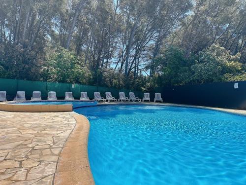 - une piscine avec des chaises et de l'eau bleue dans l'établissement studio cocooning sanary sur mer, à Sanary-sur-Mer