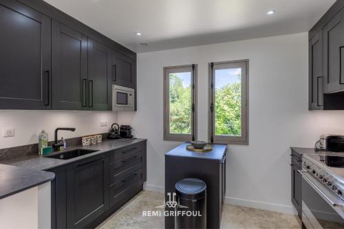 - une cuisine avec des placards noirs et un évier dans l'établissement Eva Home - Magnificent villa with Garden - Honfleur 10 Pax, à Honfleur