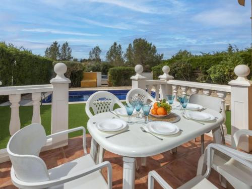 a white dining table and chairs on a balcony with a view of a pool at Villa Sueño IV by Interhome in L'Ametlla de Mar
