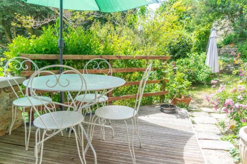 a table and chairs on a wooden deck with an umbrella at Nature et Repos in Corrèze