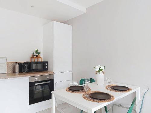 - une cuisine blanche avec une table et deux assiettes dans l'établissement Apartment Le Nice Etoile by Interhome, à Nice