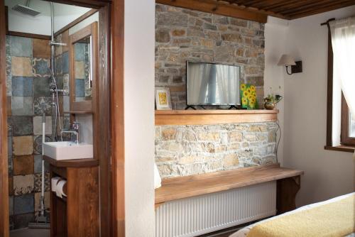 a bathroom with a sink and a stone wall at Къщата на музиканта in Leshten