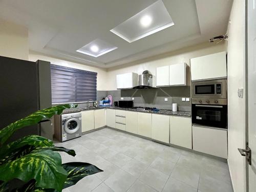 a kitchen with white cabinets and a washer and dryer at Granduer Apartment in Maiyegun