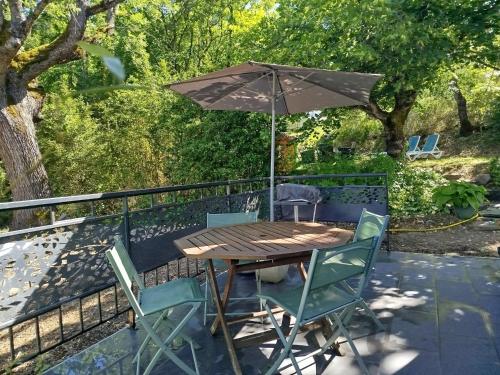 a wooden table and chairs with an umbrella at La Dame de cœur 05 in Antonaves