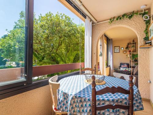 une terrasse couverte avec une table et une grande fenêtre dans l'établissement Apartment Les Mimosas Bleus-5 by Interhome, à Bormes-les-Mimosas