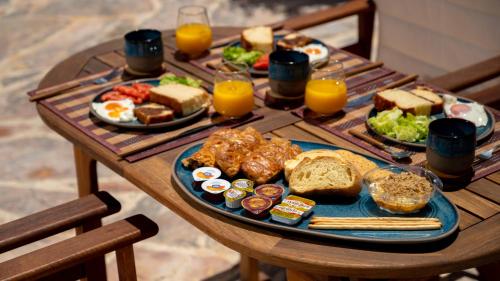 a wooden table with breakfast foods and orange juice at Blue Vine Villa Pool Breakfast in Kamari