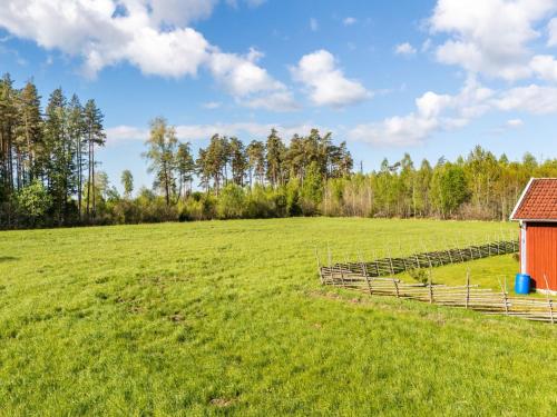 a large field with a barn and a fence at Holiday Home Strömslund by Interhome in Tävelsås