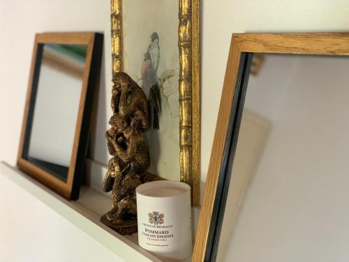 een plank met een spiegel, een kaars en een beeldje bij La Garçonnière II in Charolles