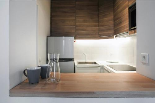 Il comprend une cuisine équipée d'un réfrigérateur et d'une table avec un vase. dans l'établissement Charmant Appartement au calme, à Levallois-Perret