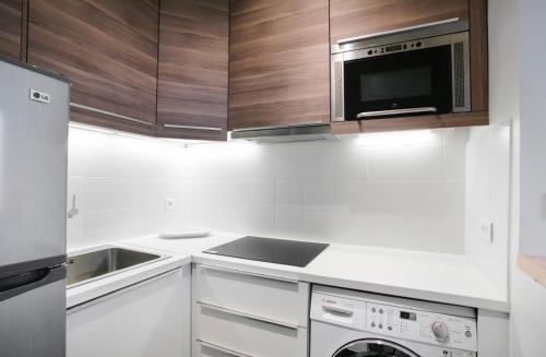 Il comprend une cuisine blanche équipée d'un four micro-ondes et d'un lave-vaisselle. dans l'établissement Charmant Appartement au calme, à Levallois-Perret
