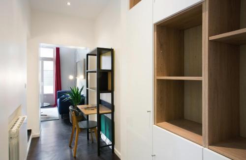 une petite pièce avec une table et un bureau avec une étagère dans l'établissement Charmant Appartement au calme, à Levallois-Perret