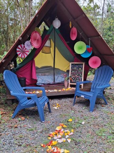 a tent with two chairs and a table and umbrellas at Glamping Montaña de Sueños in Cali