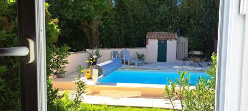 une vue d'une piscine à travers une fenêtre dans l'établissement L'Oustau dei Aucèus, à Saint-Rémy-de-Provence