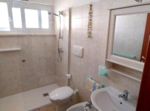 a bathroom with a toilet and a sink and a shower at Appartamento MaRi con piscina in Torre Lapillo