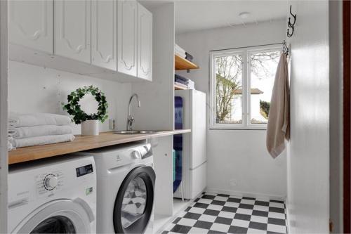 a white laundry room with a washer and a sink at Trevligt hus & Sjöbod i mysiga Mollösund Tången in Mollösund