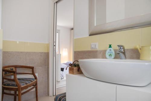 a bathroom with a white sink and a chair at Residenza La Fonte in Laveno-Mombello