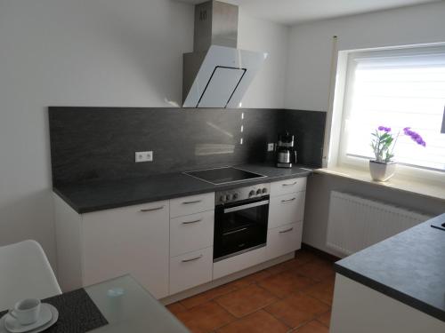 a kitchen with white cabinets and a black counter top at Ferienwohnung Schneckenhaus in Ofterdingen