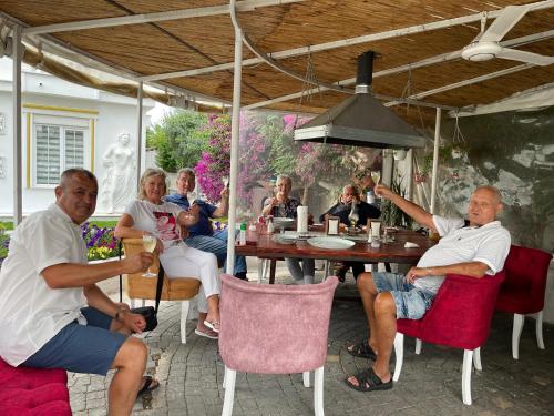 a group of people sitting around a table under an umbrella at BELKA GOLF RESİDENCE Luxury Apt Poolside Belek in Belek