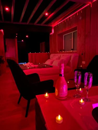 une pièce rouge avec une bouteille et des verres sur une table dans l'établissement Nature et Jacuzzi privatif, à Faverolles