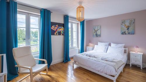 a bedroom with a bed and a chair and windows at Villa des Lilas - Champagne & SPA in Buxeuil