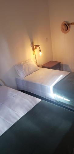 two beds in a bedroom with a light on the wall at Sítio Chã do Cajá in Sao Benedito do Sul