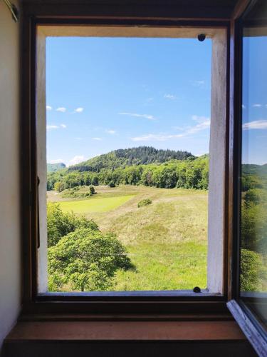 une fenêtre avec vue sur un champ vert dans l'établissement Charmante maison de village avec jardin, proche abbaye d'Hautecombe, à Saint-Pierre-de-Curtille