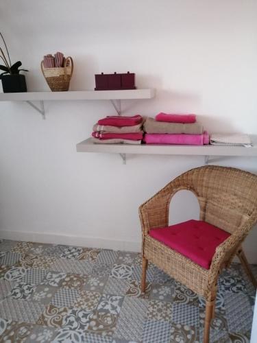 une chaise en osier assise dans une pièce avec des étagères dans l'établissement Ty Kerescar, à Plouarzel