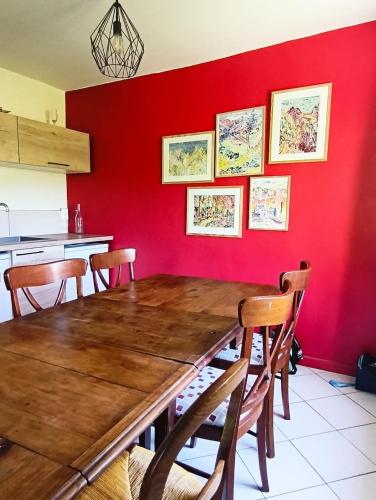 une cuisine avec une table en bois et un mur rouge dans l'établissement Charmante maison de village avec jardin, proche abbaye d'Hautecombe, à Saint-Pierre-de-Curtille