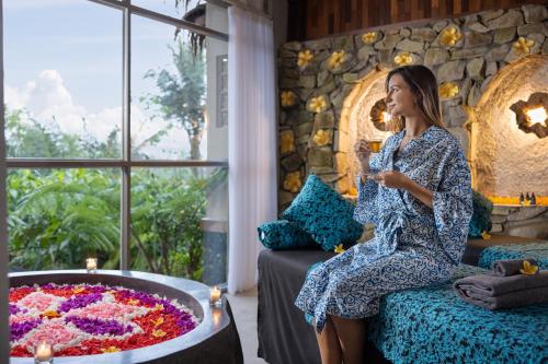 a woman sitting on a couch next to a tub of flowers at Sacred Valley by GenuineHost in Tegalalang