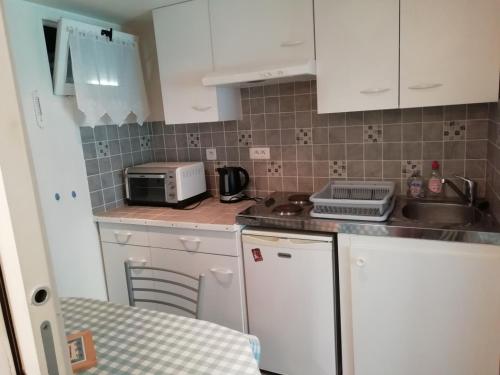 une petite cuisine avec des armoires blanches et un micro-ondes dans l'établissement Studio 20m2, à La Celle-sous-Gouzon