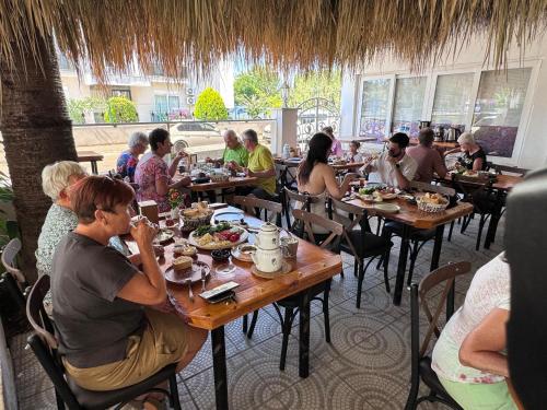 a group of people sitting at tables in a restaurant at BELKA GOLF RESİDENCE Deluxe apt Poolside BELEK in Belek