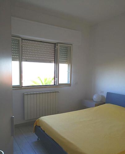 a bedroom with a yellow bed and a window at Appartamento Passeggiata Vista Mare in Viareggio