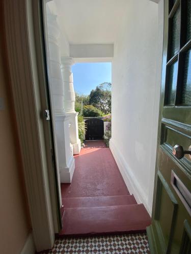 an open door to a hallway with a red floor at Artists Seaside Sanctuary in St. Leonards