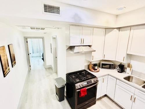 a kitchen with white cabinets and a stove top oven at Newly Built Stylish Modern 2B In LA in North Sherman Way