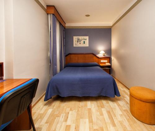 a bedroom with a blue bed and a desk at Hotel Torrepalma in Alcalá la Real
