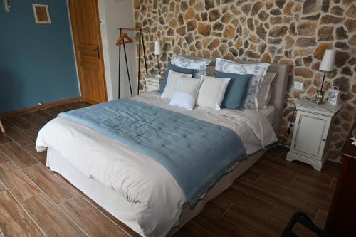 a bedroom with a large bed with blue and white pillows at Aux 3 Forêts in Bizeneuille