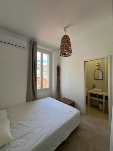 - une chambre avec un lit blanc, une fenêtre et un lavabo dans l'établissement New and air-conditioned cocoon, à Marseille