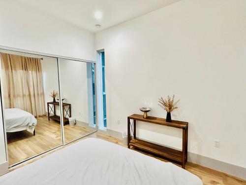 a white bedroom with a mirror and a bed at Newly Built Stylish Modern 2B In LA in North Sherman Way