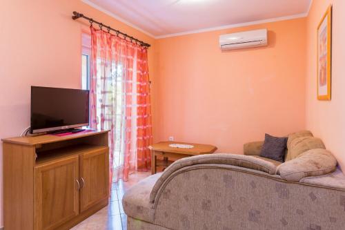 a living room with a couch and a flat screen tv at Apartments Villa Orange in Medulin
