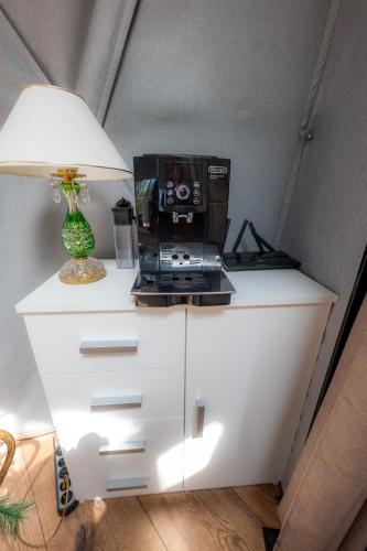 a microwave sitting on top of a white cabinet with a lamp at Kamieńczyk Glamp - pod Warszawą in Kamieńczyk