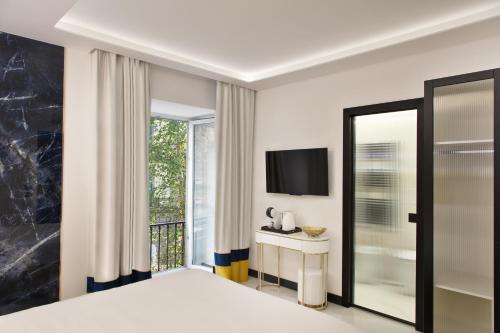 Incanto Suites Italy في نابولي: غرفة نوم بها سرير وتلفزيون ونافذة