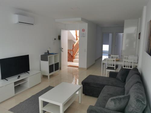 Una sala de estar con un sofá y un televisor. en Residencial Amber II - Apartamento nuevo, amplio y cómodo, en Vecindario
