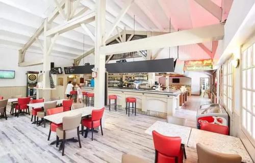un restaurant avec des chaises rouges, des tables et un comptoir dans l'établissement Bungalow accueillant à Saint-Jean-de-Monts avec piscine, à Saint-Jean-de-Monts