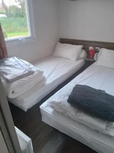 deux lits assis dans une pièce avec une fenêtre dans l'établissement Bungalow idéal à Saint-Jean-de-Monts avec piscine, à Saint-Jean-de-Monts